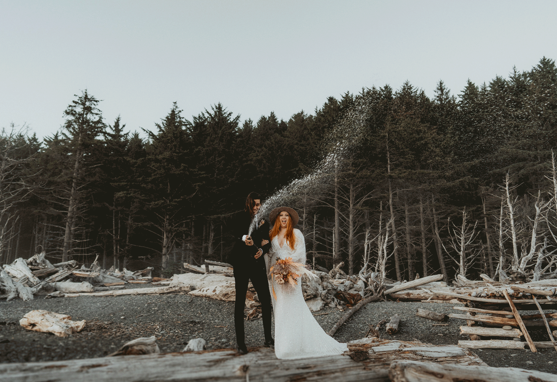 Emily and Austin on their wedding day, popping a bottle of champagne.